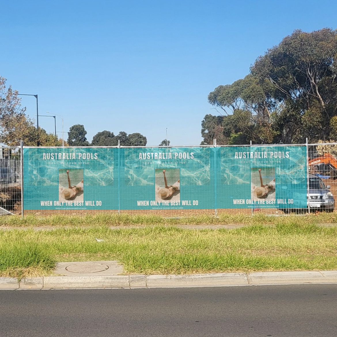 Three identical billboard mesh banners of Australia Pools on a fence with trees and a clear sky in the background.
