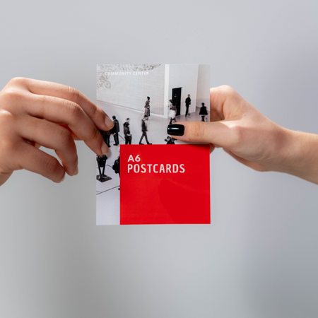 A6 postcards held by two hands against a light gray background