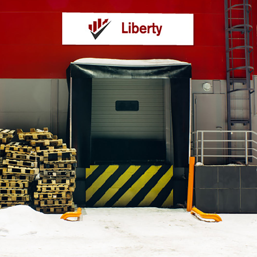 Dock with a covered door, pallets, and a Liberty logo sign on aluminium composite panel on a red wall.