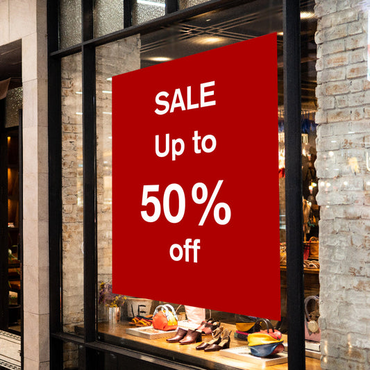Red sale sign in a store window advertising up to 50% off.